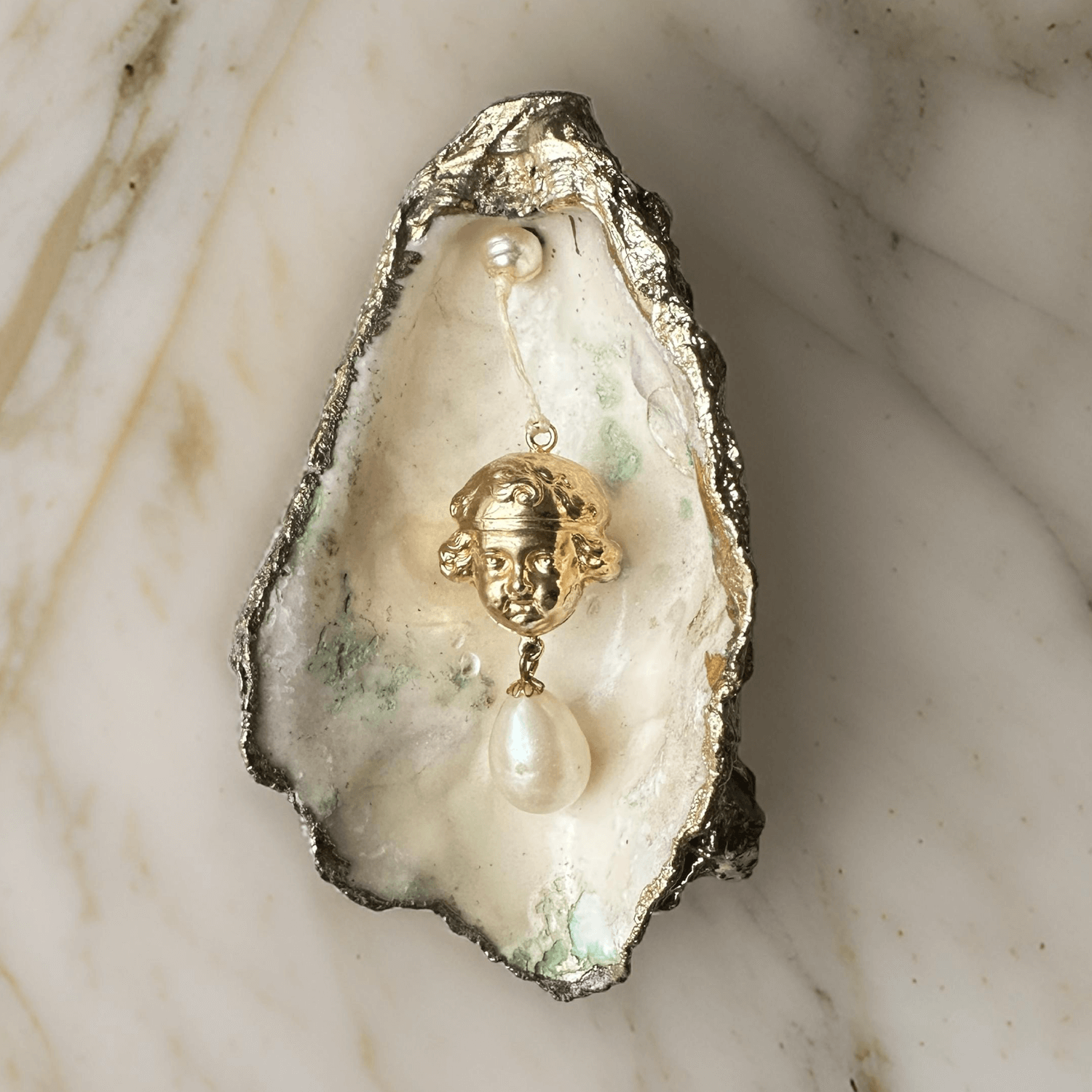 Oyster shell with pendant shiny cherub head with pearl ei nzigartig