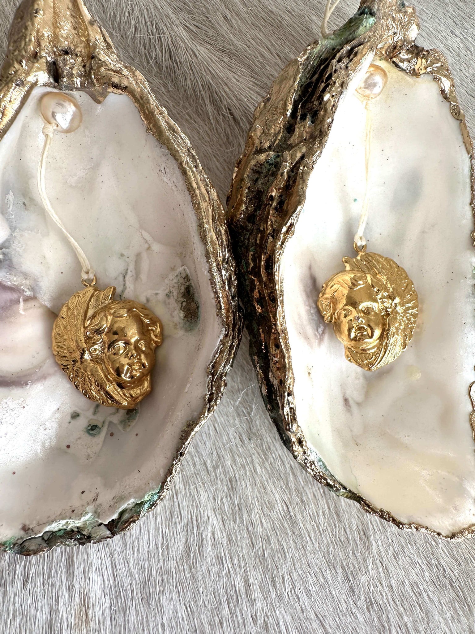 Oyster shell with pendant: shiny putti head, left 